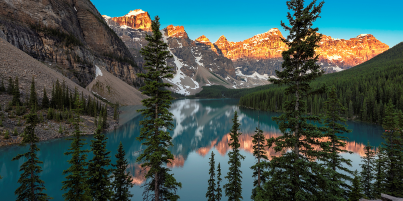 Photo of Canadian rocky mountains with trees and a lake.