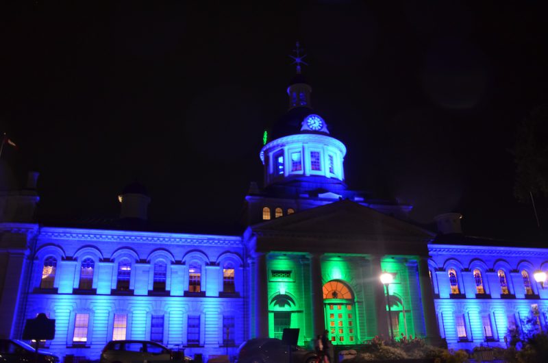 Kingston City Hall building in the dark, lit up blue and green