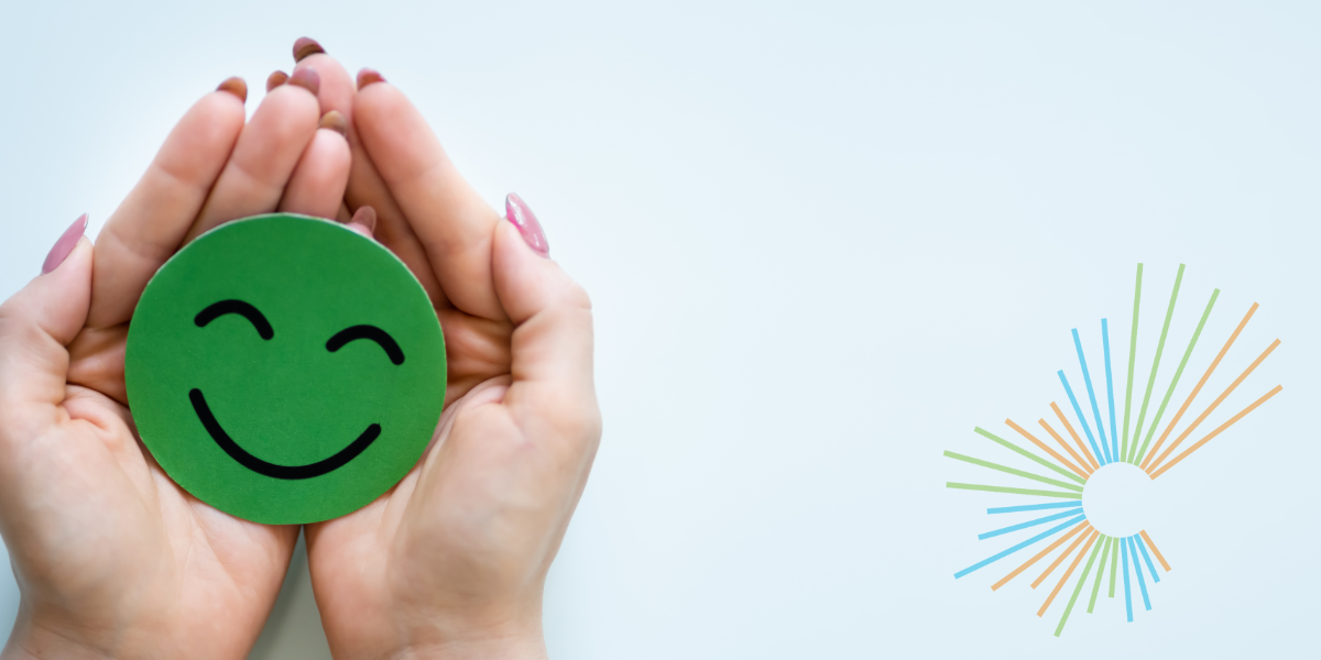 On the left, two hands cradle a wooden disk, whose surface is painted green and embellished with a happy face. Atop a powder blue background sits the Circular Economy Month starburst logo on the right.